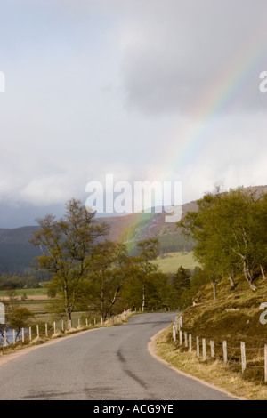 Rainbow and single track road in scottish glen, Braemar, Cairngorm National park, scotland uk Stock Photo
