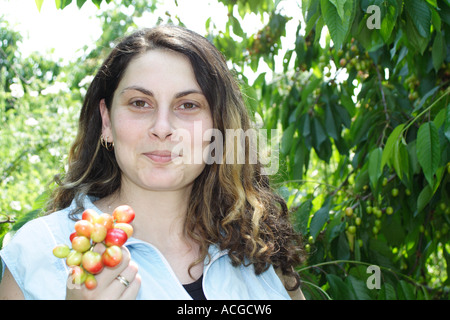 Young woman smiling and holding bunch of cherry Stock Photo