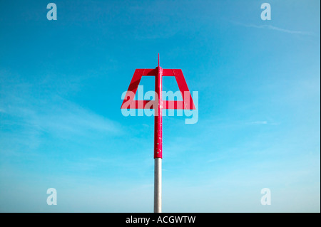 A bright red beach marker situated on a sea defence wall break. The tide is coming in with relaxing waves and blue sky Stock Photo