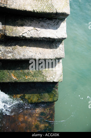 Several concrete coastal weathered steps leading into the wavy sea Stock Photo