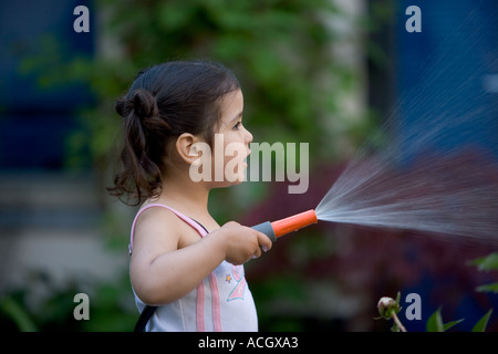Little girl with a garden hose Stock Photo