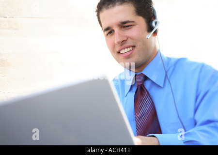 Young businessman working on laptop with headset on Stock Photo