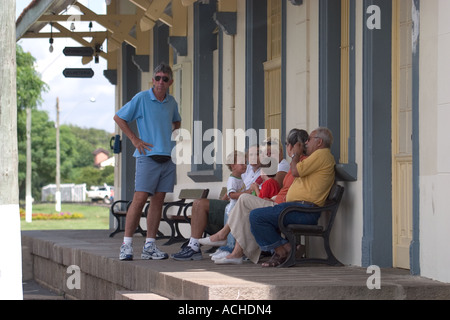 Family waits in shade of train platform Stock Photo