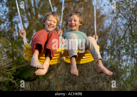 Eight-year-old and ten-year-old boys swinging happy Stock Photo