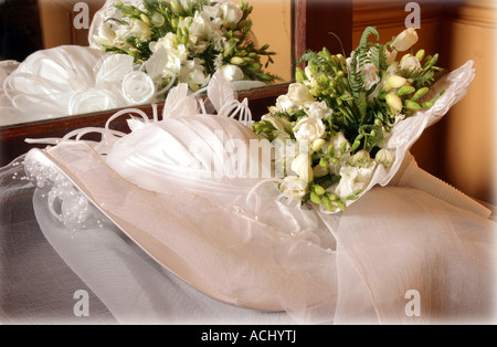 A portrait of a white traditional wedding dress pictured here in a presentation box with a bouquet of flowers on top of it. Stock Photo