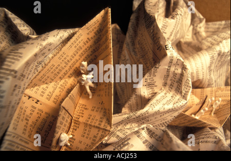 Small figures on a paper boat made from a newspaper page with stock market quotations Stock Photo
