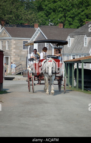 A horse drawn carriage gives tourists rides at Mystic Seaport in Connecticut Stock Photo