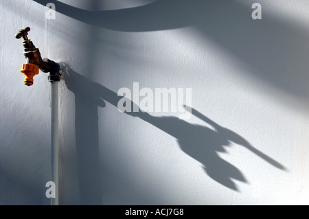 The shadow of a greenhouse water tap on a white painted wall Stock Photo