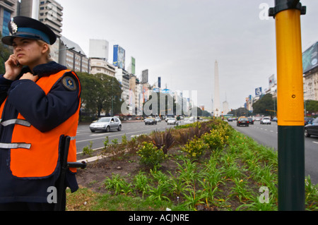 The obelisk, obelisco, on the Plaza de la Republica Square on the Avenida 9 Julio Avenue of ninth of July, a woman police man in the foreground. Traffic. Modern office buildings. Buenos Aires Argentina, South America Stock Photo