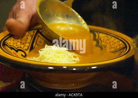 Provencal Soupe de poisson de roche, rock fish soup with grated cheese being served in a bowl, often served with Rouille garlic Stock Photo