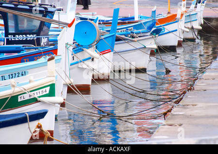 Typical Provencal fishing boats painted in bright colours white, blue, green red yellow, moored at the keyside Sanary Var Cote d’Azur France Stock Photo