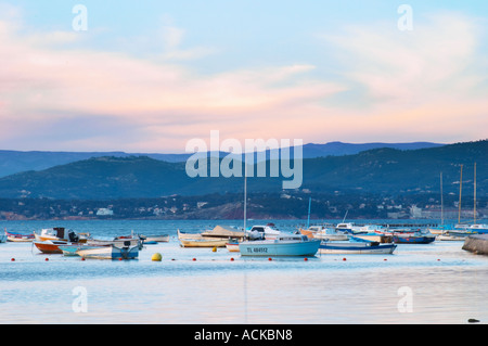 View from Sanary over the sea towards the mainland mountains at sunset, light faded blue, Provencal boats moored at buoys in the water Le Brusc Six Fours Var Cote d’Azur France Stock Photo