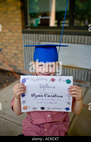 A small boy shows his diploma at a pre-school daycare graduation ceremony Stock Photo