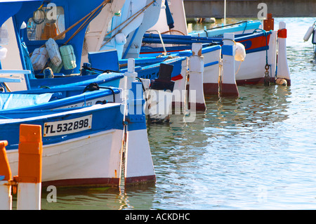 Typical Provencal fishing boats painted in bright colours white, blue, green red yellow, moored at the keyside Sanary Var Cote d’Azur France Stock Photo