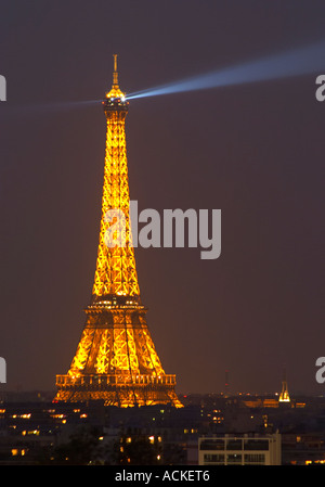 The Eiffel Tower in Paris illuminated at night against a dark blue black sky, search light ray on the sky, illumination golden yellow Paris France Stock Photo