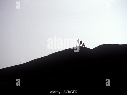 Three Climber Hikers Silhouette On Mountain Top, Ayers Rock Australia Stock Photo