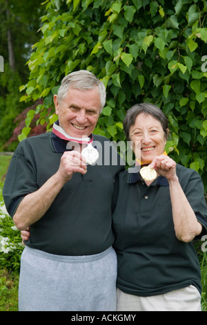 Healthy active elderly retired seniors holding up gold and silver award medals on ribbons Stock Photo