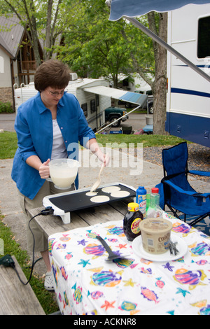 A woman prepares a pancake breakfast on a griddle outdoors at a RV resort park in Pigeon Forge, Tennessee, USA Stock Photo