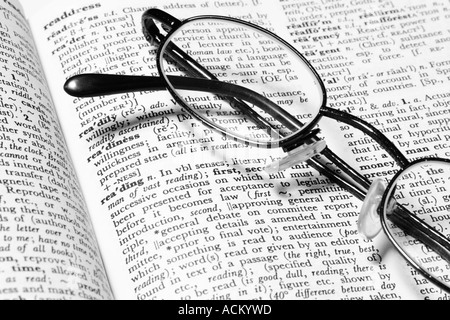 Reading glasses resting on a dictionary open at the definition for the word reading Stock Photo