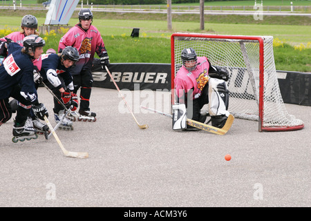 Kids playing street hockey on asphalt with inlines, hockey sticks and a ball Stock Photo