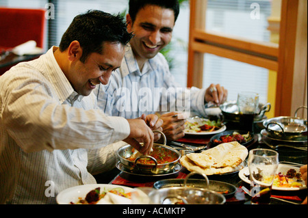 Two Asian men enjoying a balti meal at a restaurant in Ladypool Road in Birmingham, UK Stock Photo