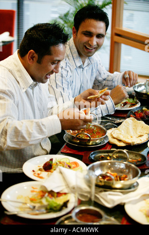 Two Asian men enjoying a balti meal at a restaurant in Ladypool Road in Birmingham, UK Stock Photo