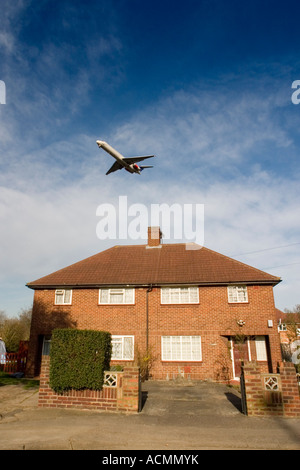 Low flying passenger airplane over houses on approach to London Heathrow airport Feltham Middlesex England UK Stock Photo