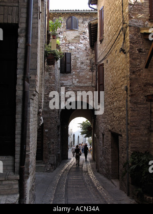 Roman arch over narrow stone path leading downhill between houses in hilltown village of Spello Italy Stock Photo