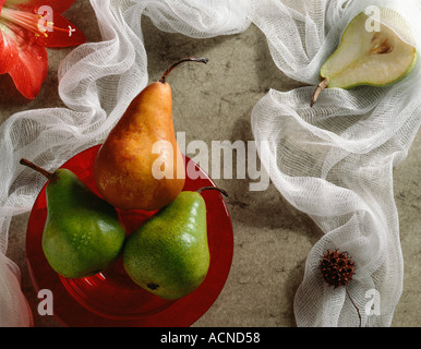 A group of Bosc and Anjou Pears in a red bowl illuminated by late afternoon light Stock Photo