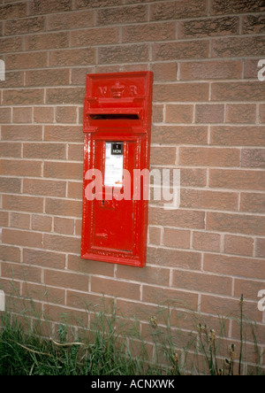 Red Victoria Regina Royal Mail postbox in brick wall Stock Photo