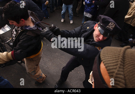 A police officer police man grabs a protester by the collar during a massive protest in New York against the war in Iraq Stock Photo