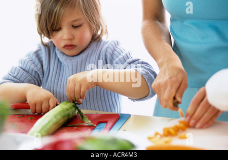 Son (4-7) and mother cutting vegetables, close-up