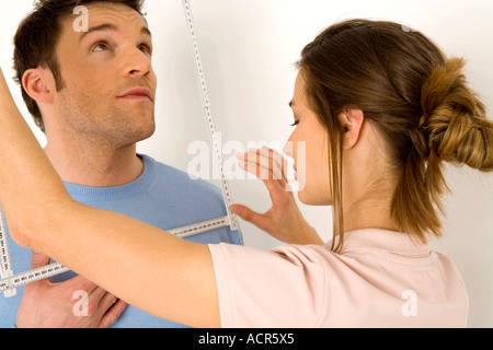 Woman measuring man's face with ruler, close-up Stock Photo