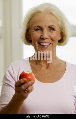 Senior woman eating apple, smiling, close-up, portrait Stock Photo