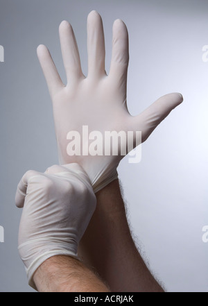 A pair of male hands putting on latex rubber gloves Stock Photo