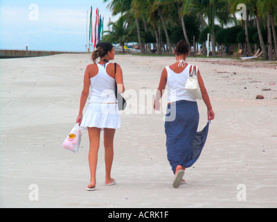 Two young women walk on Pantai Cenang beach Pulau Langkawi island Malaysia Stock Photo