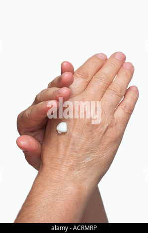 Mature woman rubbing lotion on hands close up of hands Stock Photo