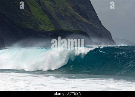 Salt spray of wave breaking on Kalaupapa leper colony beach with steep cliffs on Molokai Hawaii Stock Photo