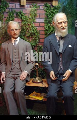 WAX EFFIGIES OF THOMAS ALVA EDISON AND ALEXANDER GRAHAM BELL SHOWN SITTING ON A BENCH WITH A TELEPHONE IN THE MIDDLE Stock Photo