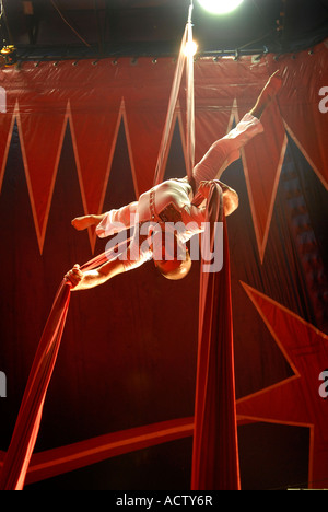 Circus acrobat performer tangled in red drapes Stock Photo