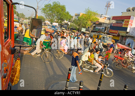 Typical busy junction on the outskirts of Delhi with motorbikes, push bikes, cycle rickshaws and people all crossing the road at Stock Photo