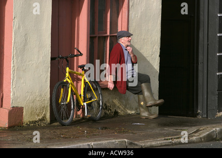 Ireland County Donegal Mountcharles High Street man relaxing sat on window ledge Stock Photo