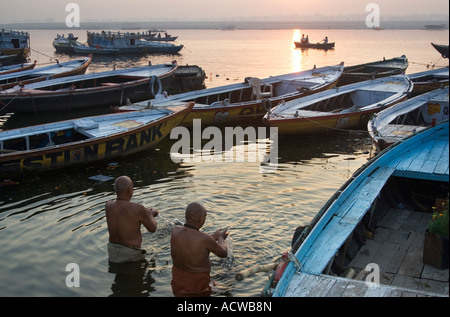 Men praying between boats in the Ganges Varanasi Benares India Stock Photo