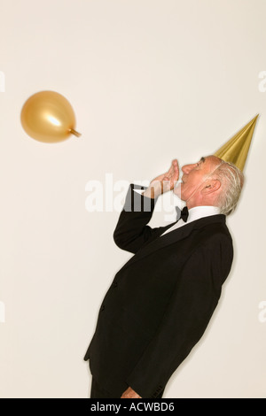 Senior man inflating a balloon Stock Photo