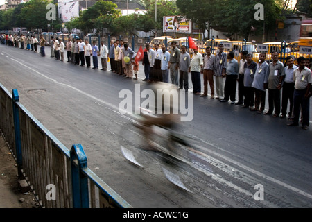 A lonely biker crossing in front of a civic rights march Calcutta Kolkata India Stock Photo