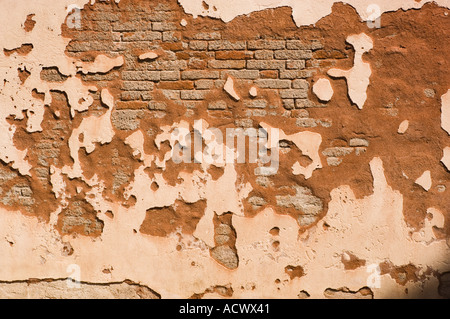 pink stuccoed brick wall with chipped stucco and peeled paint revealing the brick on a wall in Venice Italy
