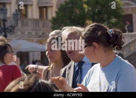 Editorial use only No model release teenage girls flanking and elderly man singing and clapping in April 9 Plaza in Taormina Stock Photo