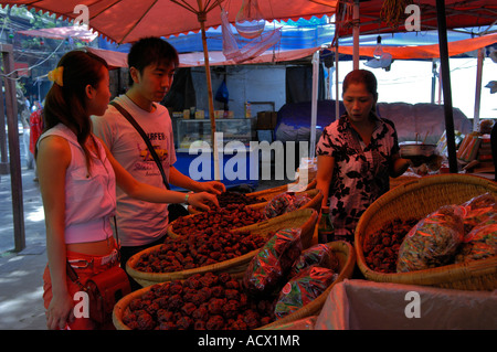 A young Chinese couple shopping for dates at an outdoor market in the Muslim Quarter of Xian, China Stock Photo