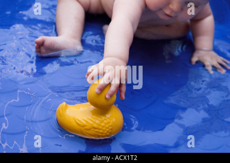 Baby in wading pool reaching for 'rubber ducky.' Stock Photo