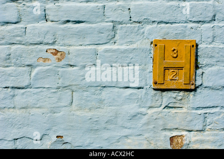 yellow fire hydrant sign on blue painted brick wall aberystwyth ceredigion Stock Photo